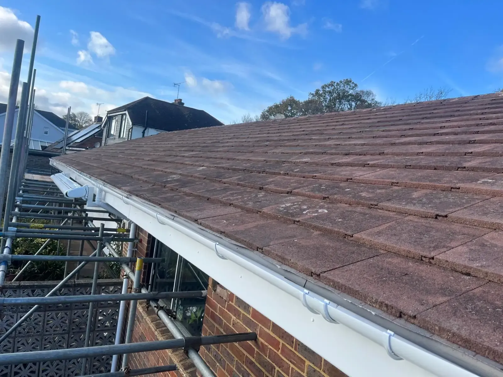 A retiled roof and new gutter by Fully Covered, scaffold alongside, blue sky