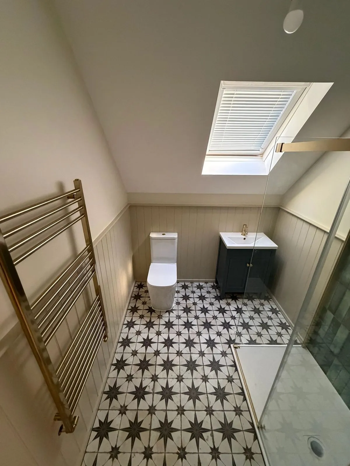 A bathroom fitted by Rabiu Plumbing and Heating: star-tiled floor, brass towel rail