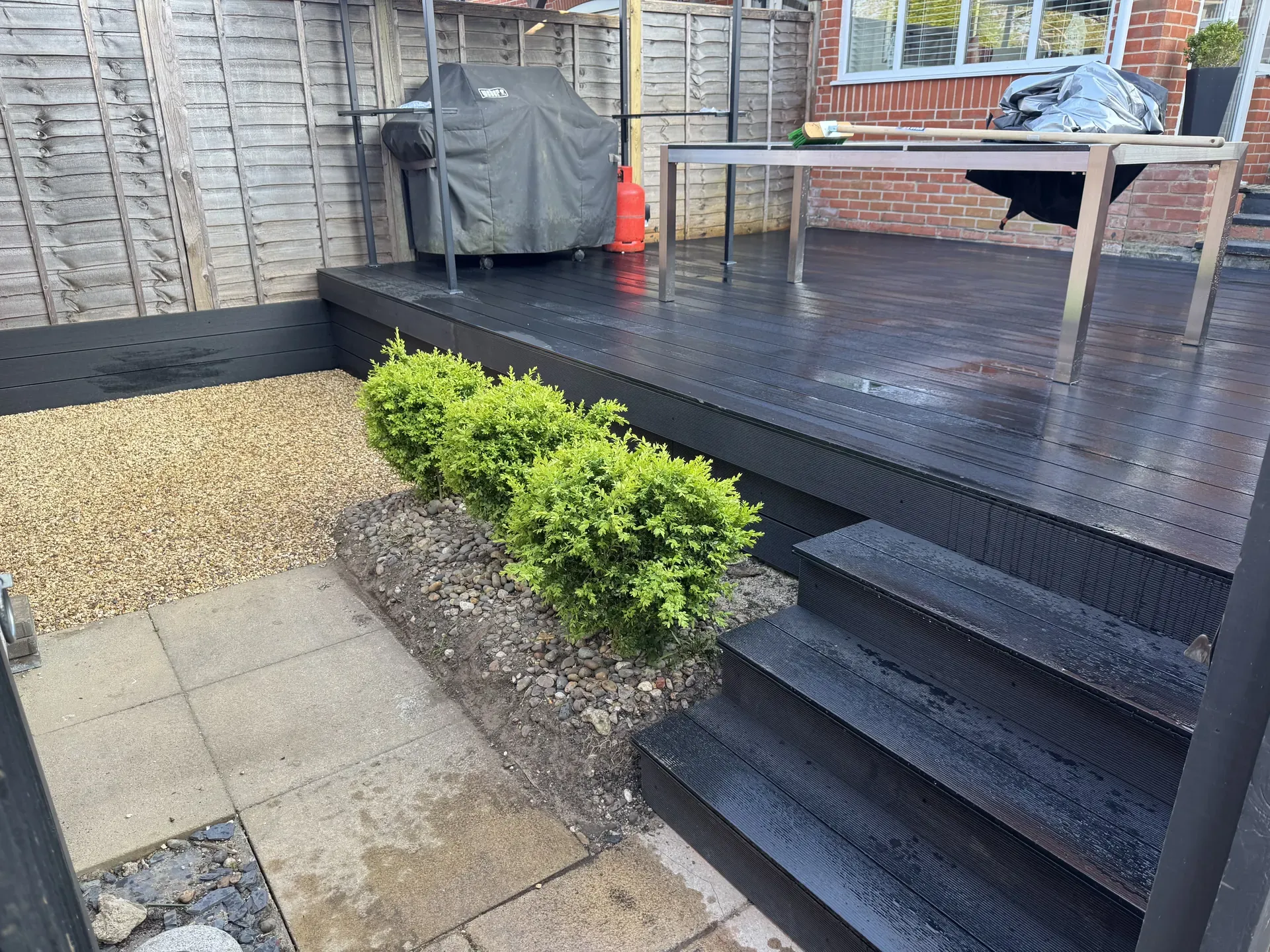 Dark composite decking, steps and planting by RNH Building Solutions